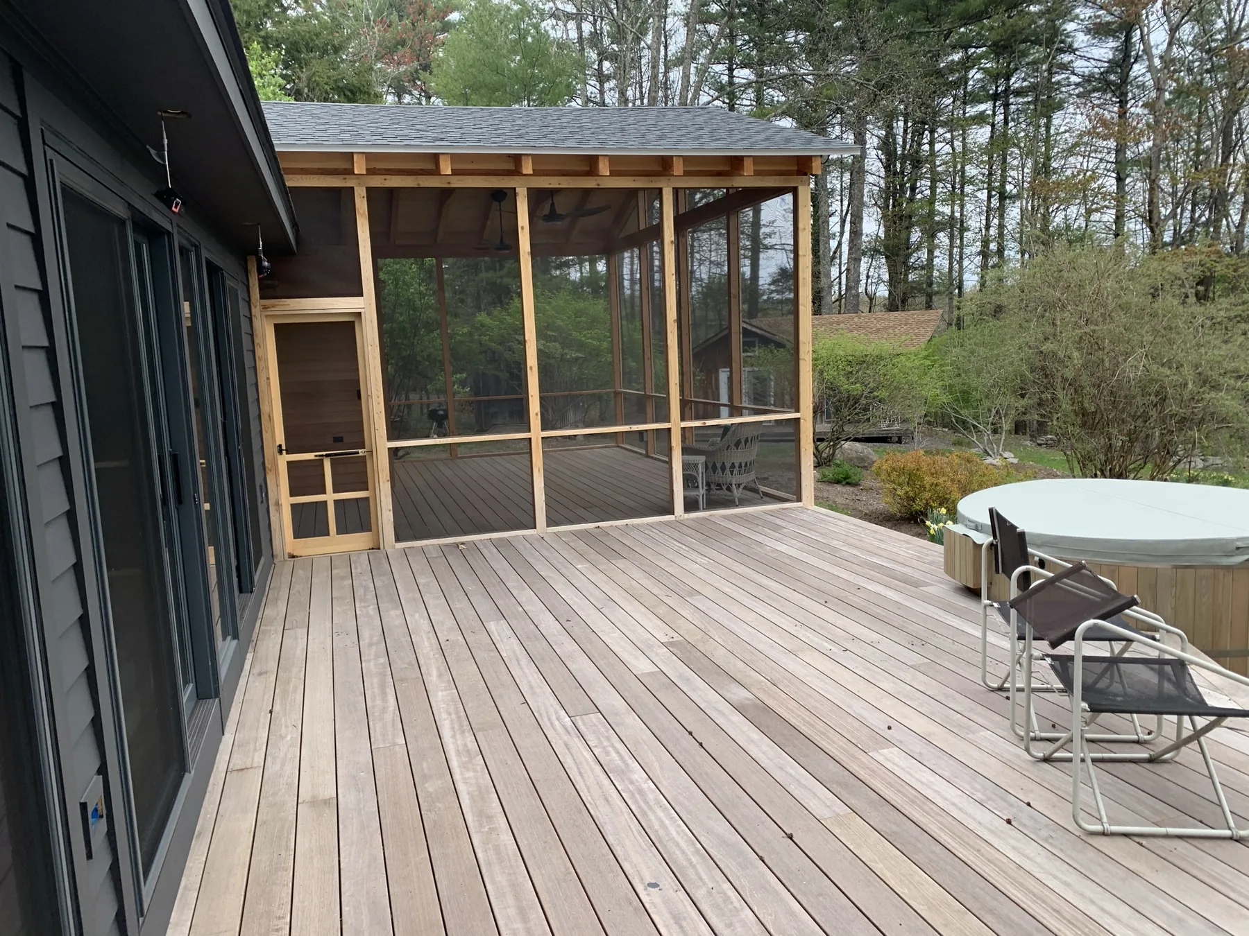 Wide ipe deck leading to a newly framed screened porch with a cedar screen door