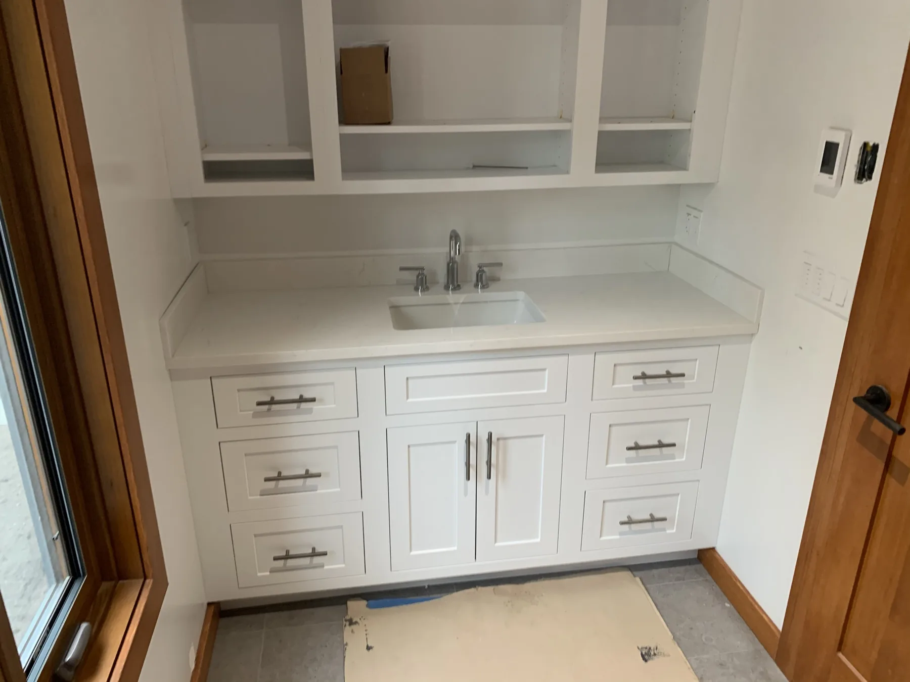 White shaker vanity with a quartz countertop, undermount sink, and painted open shelving above